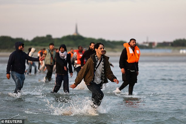 A group of migrants run from the beach into the water to reach an inflatable dinghy to leave the coast of northern France in an attempt to cross the English Channel to reach Britain as tougher migration controls were announced, at the beach of Petit-Fort-Philippe in Gravelines, near Calais, France, July 17,
