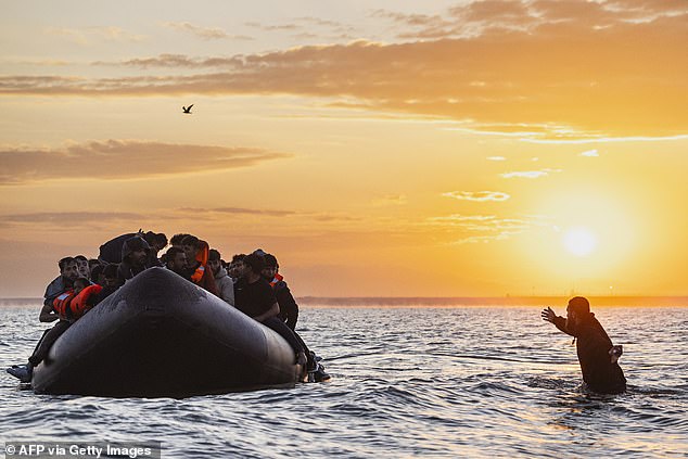 A migrant tries to board a smuggler's inflatable dinghy in an attempt to cross the English Channel off the beach of Gravelines, northern France on July 29, 2025