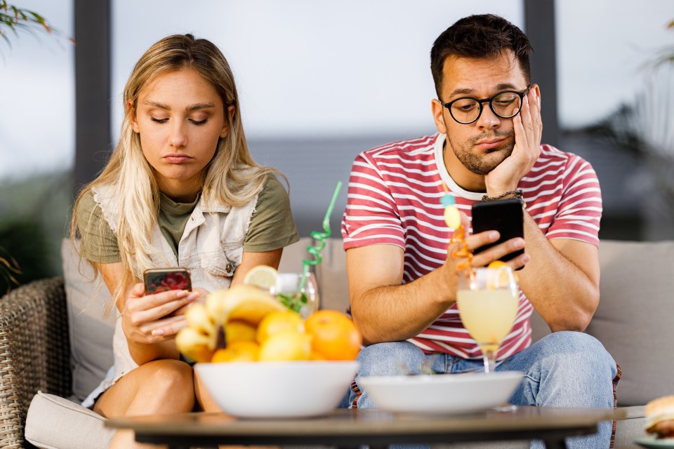 A young couple ignores each other while using their mobile phones.