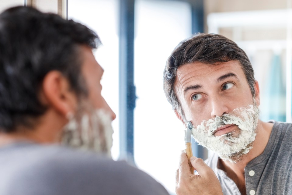 Man shaving in a bathroom mirror.