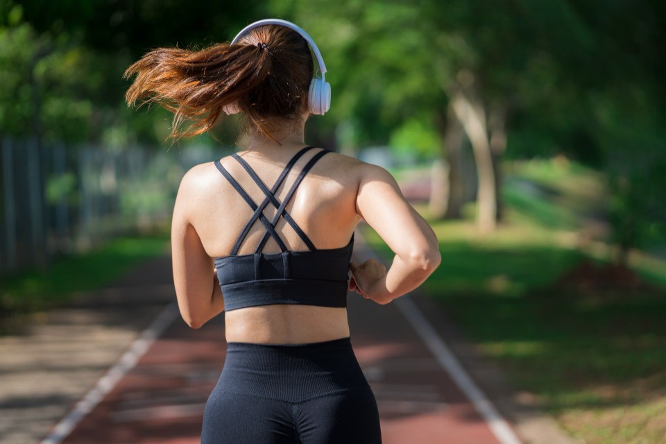 Woman jogging in a park while listening to music.