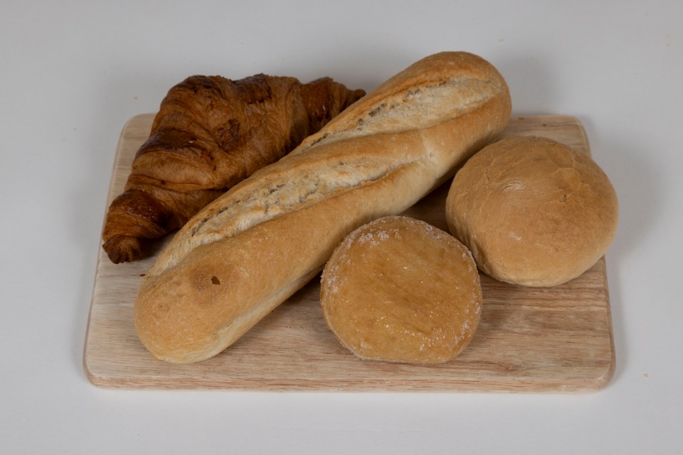 Croissant, baguette, and rolls on a wooden board.