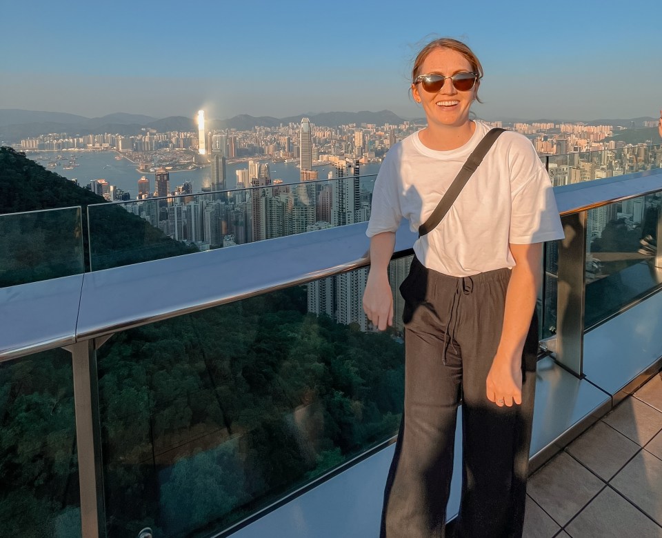 Woman smiling on a Hong Kong viewing platform overlooking the city.