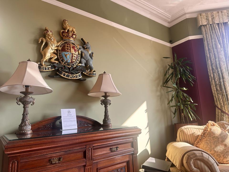 Interior of a room with a coat of arms, lamps, and a wooden cabinet.