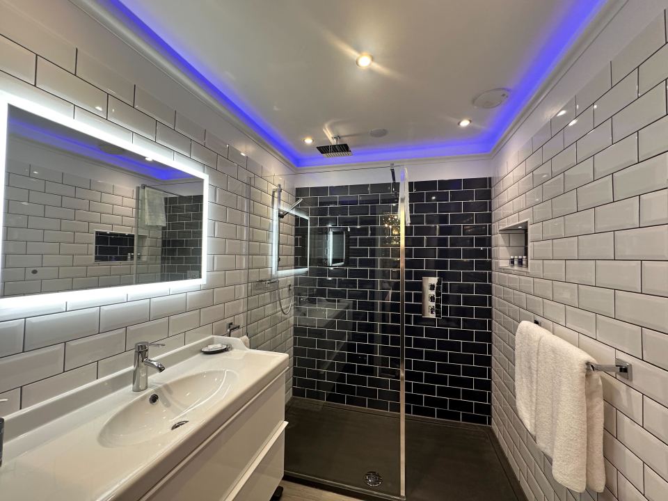 Bathroom with white and black tile, walk-in shower, and vanity.
