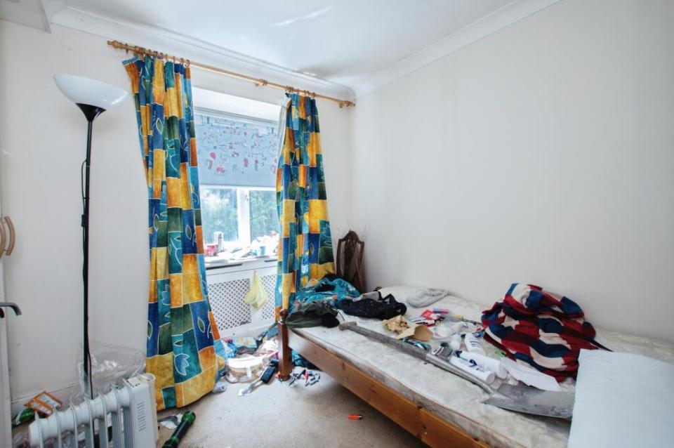 Messy bedroom with cluttered bed and floor.
