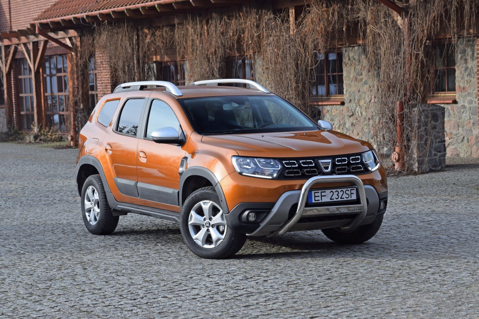 Orange Dacia Duster parked in front of a building.