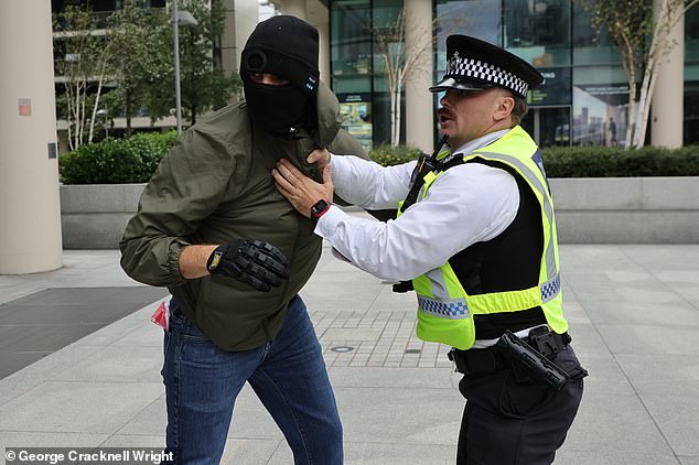 A masked protesters clashes with police at today's protest in Canary Wharf, London