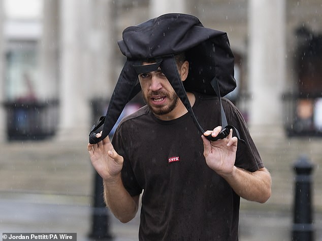 A man makes a makeshift cover to shelter from the morning rain in Trafalgar Square on July 31