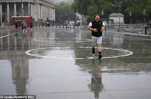 man jogging in the morning rain in Trafalgar Square, central London, on July 31