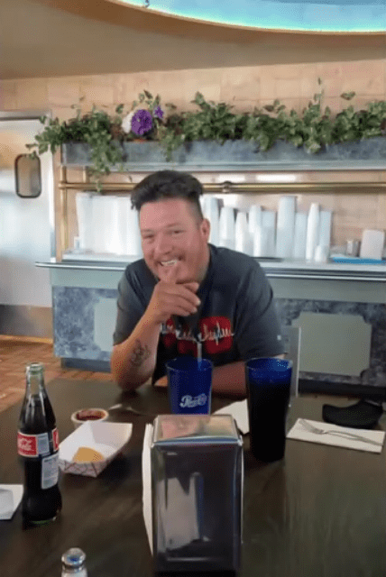 A smiling man sitting at a table in a restaurant.