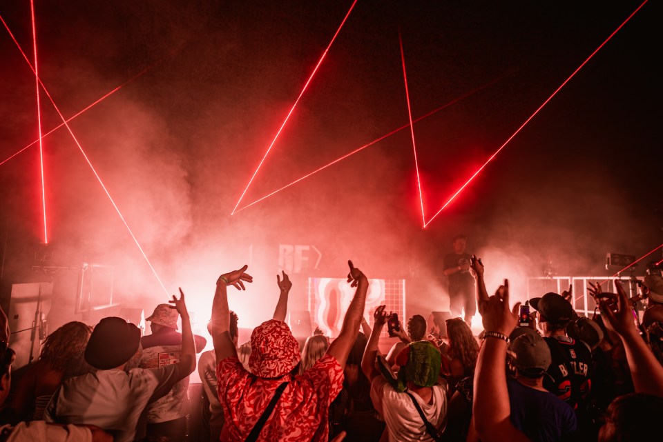 Crowd at a music festival with red laser lights.