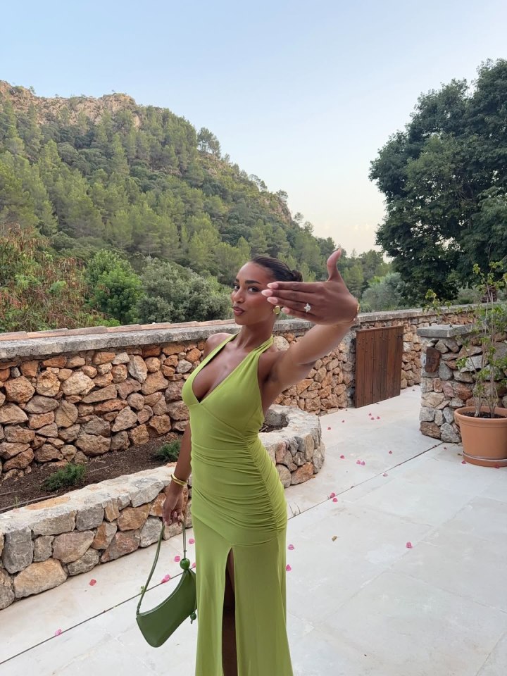 Woman in green dress showing off engagement ring.