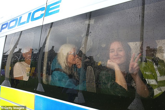 A supporter of Palestine Action gives a 'V' sign as they are arrested and put in a police van after holding up a sign supporting a proscribed group on July 19, 2025 in London
