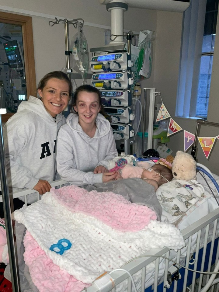 Two women with a young girl in a hospital bed.