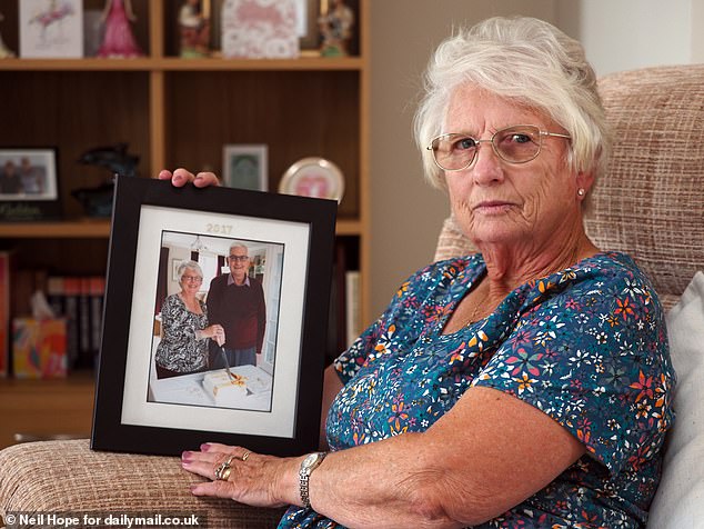 Lt Commander Jeffrey Picken, 69, served on five ships and five submarines, all while being exposed to asbestos that had been installed in the vessels for its fire-retardant properties. He died from mesothelioma on New Year’s Day in 2018. Pictured: His widow, Veronica, 77, holding a photograph of her and her husband