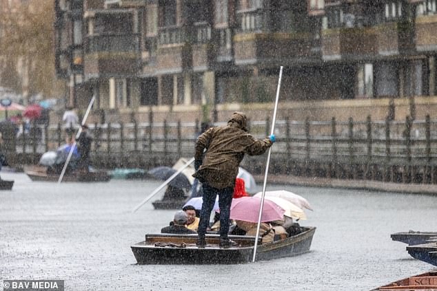 People hide under umbrellas on the River Cam in Cambridge today as Storm Herminia hit Britain in January