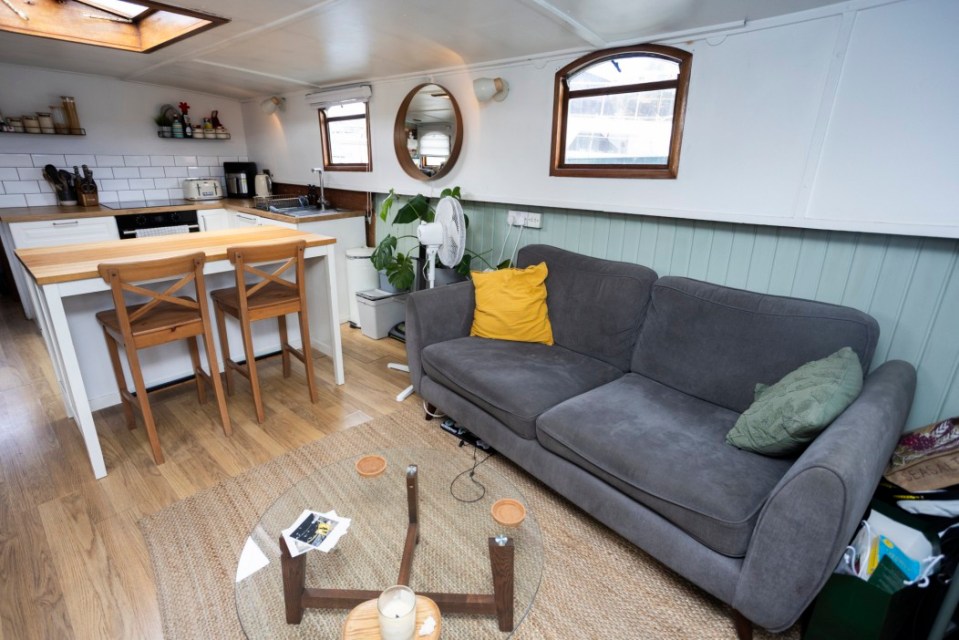 Interior of a houseboat showing a living area with a sofa and a kitchen area.