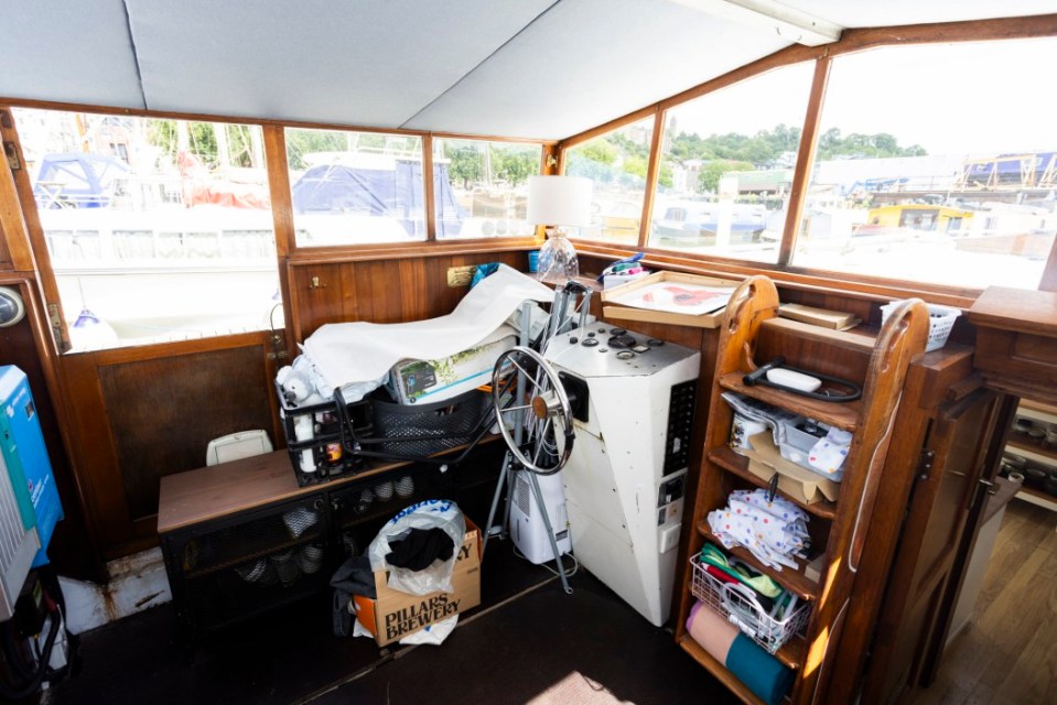 Interior of a houseboat cluttered with boxes and belongings.
