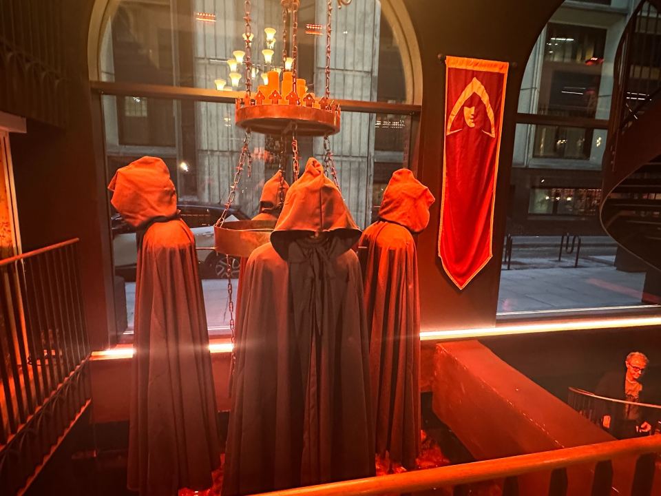 Figures in hooded cloaks at The Traitors experience.