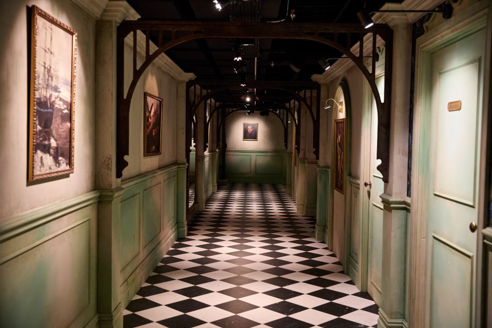 Hallway with black and white checkered floor and framed pictures on the walls.