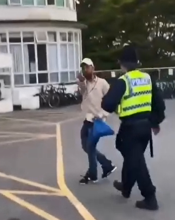 Asylum seeker giving the middle finger to protesters outside a hotel.