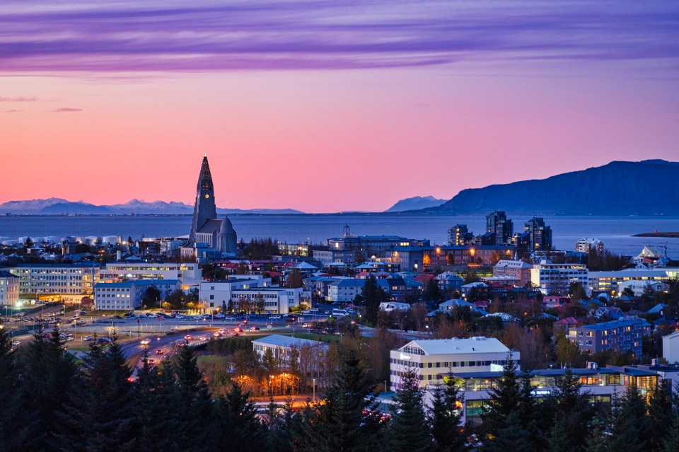Night cityscape of Reykjavik, Iceland, with a church and harbor at sunset.