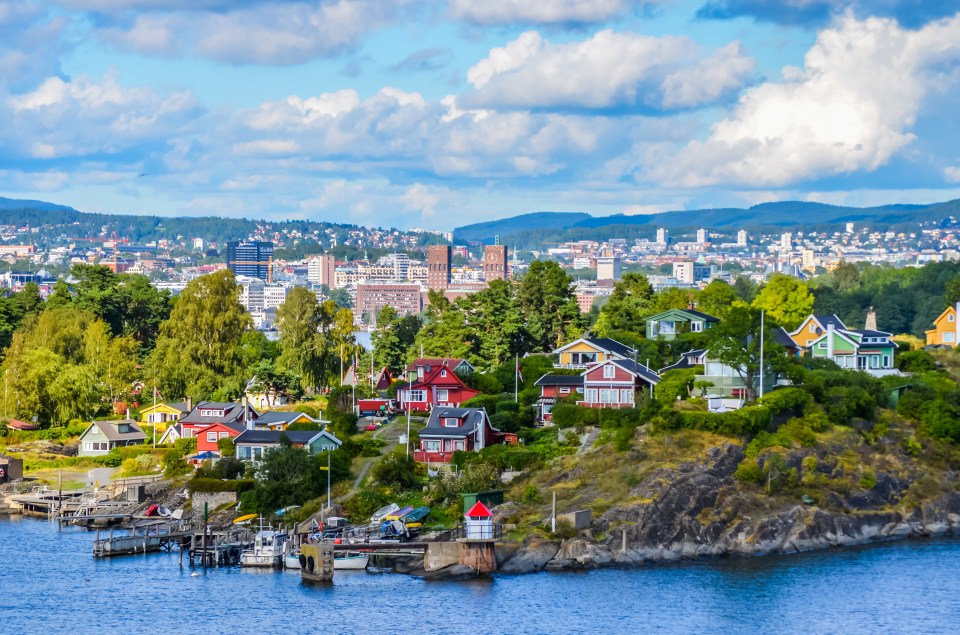 View of Oslo, Norway, with colorful houses on a small island and the city skyline in the background.