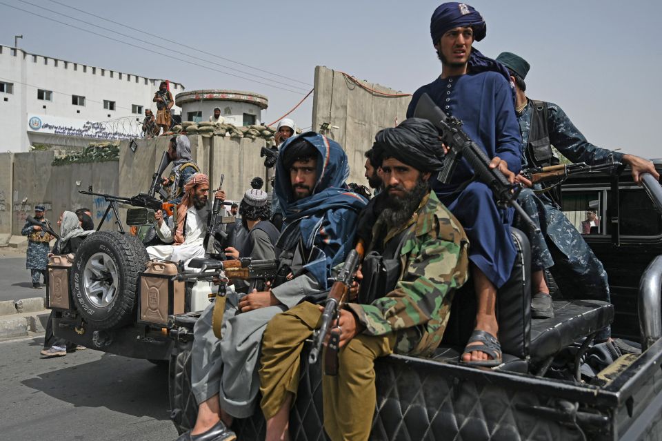 Taliban fighters escorting veiled women at a pro-Taliban rally.