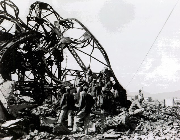 American soldiers examine the twisted wreckage of a building in Hiroshima in the aftermath of the atomic bomb attack on the city