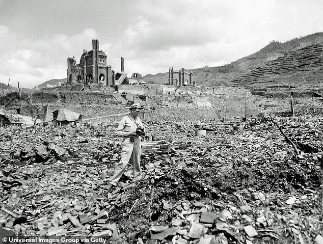 An American military official stands with what appears to be a camera amidst the rubble of destroyed buildings in the aftermath of the bombing of Hiroshima