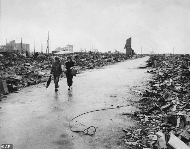 Two people walk down a path that has been cleared through the rubble of ruined buildings in Hiroshima, September 8, 1945