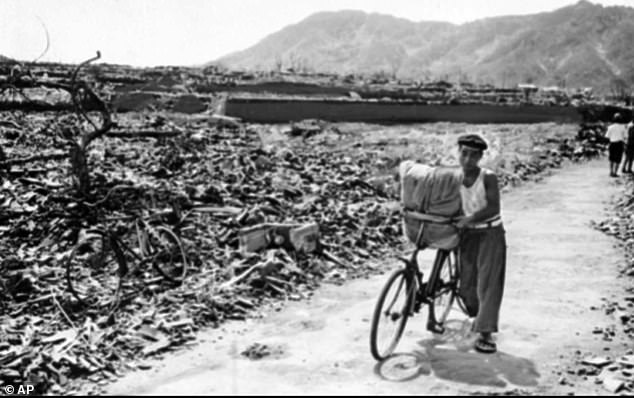 A Japanese man pushes his loaded bicycle down a path that had been cleared of rubble in Hiroshima, September 1945