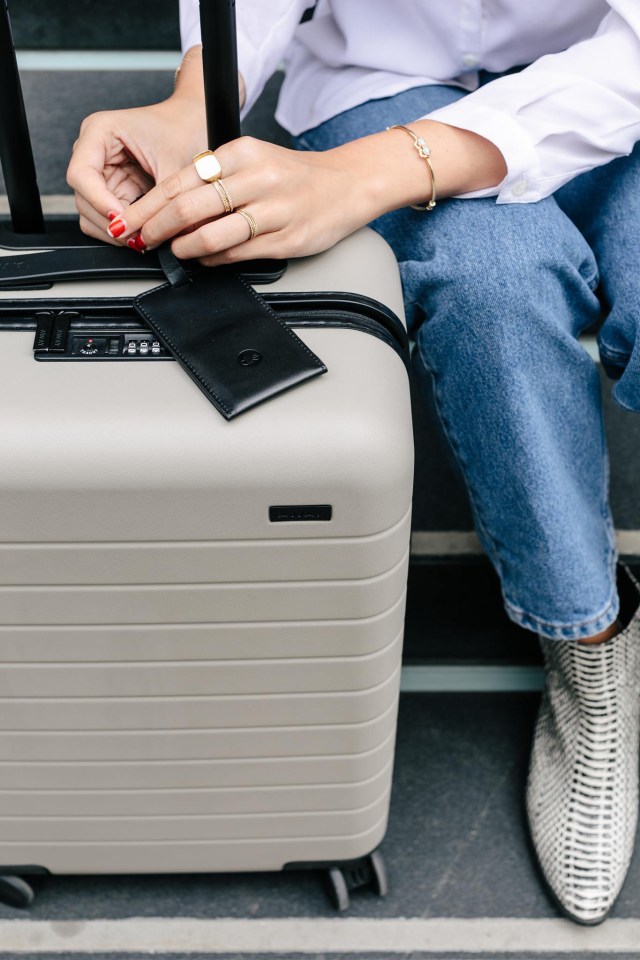 Person attaching a Tile luggage tag to a suitcase.