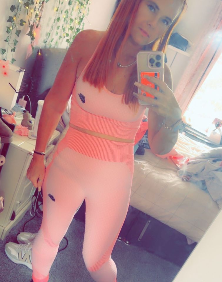 Woman in pink Nike workout outfit taking a selfie.