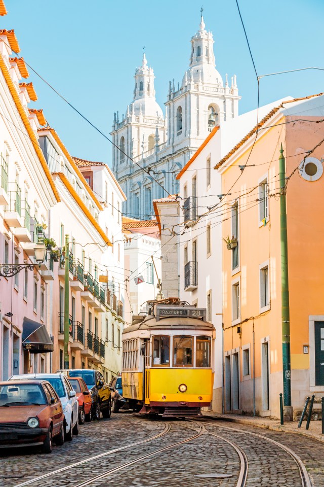 Yellow tram on cobblestone street in Lisbon, Portugal.