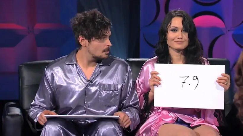Screenshot from Sex Box showing a man and woman in pajamas holding up a score of 7.9.