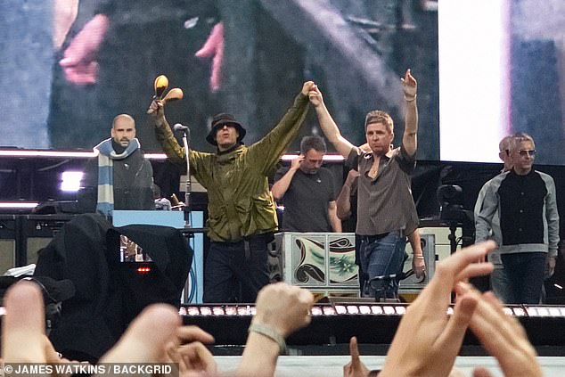 The Gallagher brothers walk on to the Wembley Stadium stage holding hands on July 26