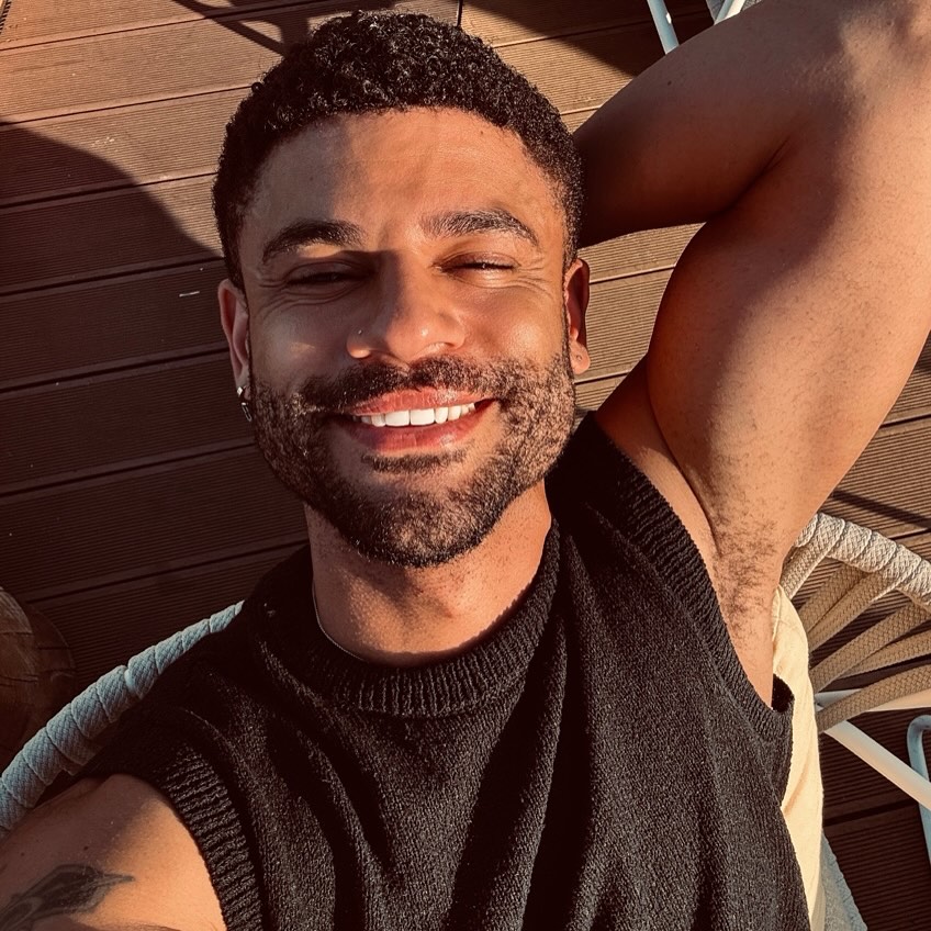 Smiling man in a black sleeveless shirt.