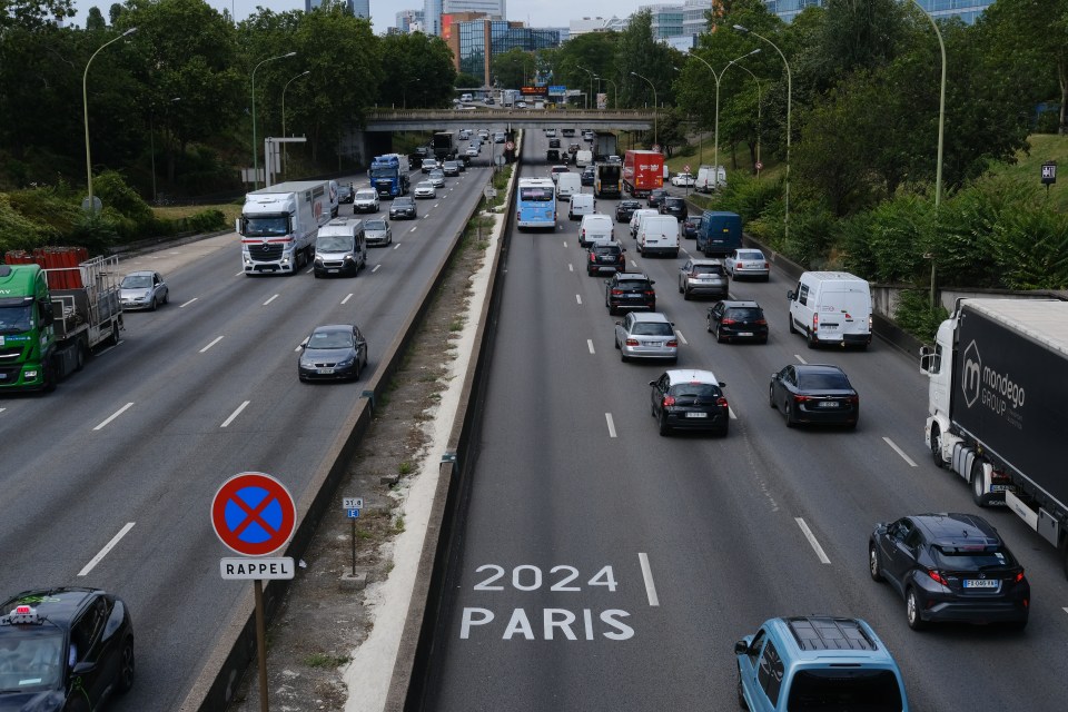 Parisian ring road traffic with "2024 PARIS" painted on the road.