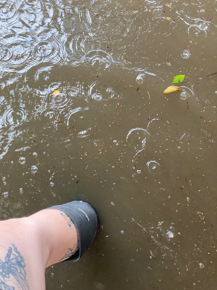 Floodwater with a person's leg in a rain boot.