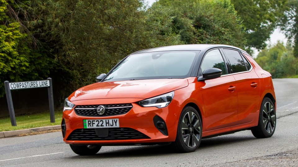 Orange Vauxhall Corsa E electric car driving on a road.