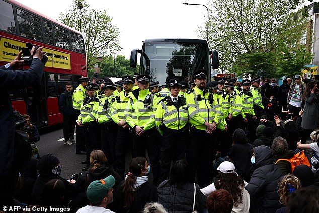 Metropolitan Police officers surround a bus reportedly waiting to remove migrants and asylum seekers from a hotel in Peckham