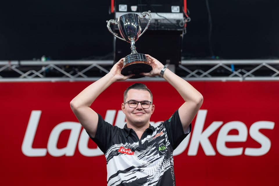 Gian van Veen holding the Winmau World Youth Championship trophy.