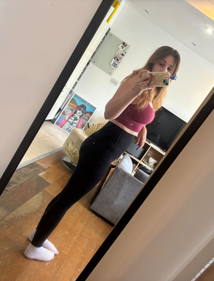 Woman taking a mirror selfie in workout clothes.