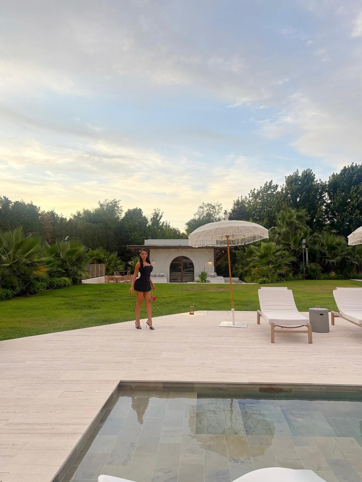 Woman in black dress by a pool.