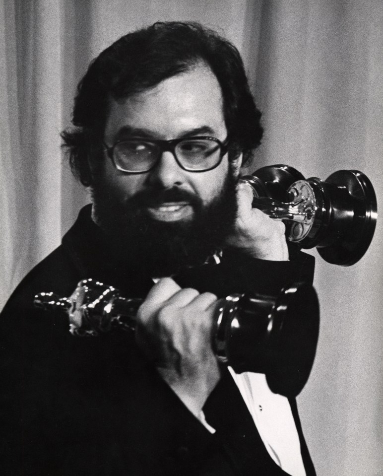 Francis Ford Coppola holding two Academy Awards.