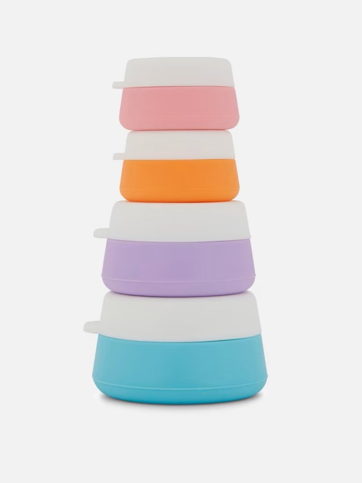 Four stacked silicone travel jars in pink, orange, lavender, and blue.