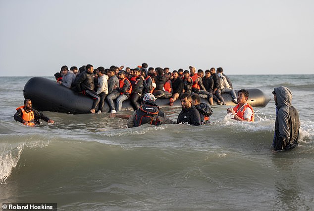 The groups of migrants spread over a mile of shoreline, gathering in three bunches, with one bunch stood a little back on the beach, and the other two groups in the water up to their waists