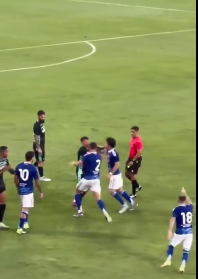 Soccer players arguing with a referee on the field.